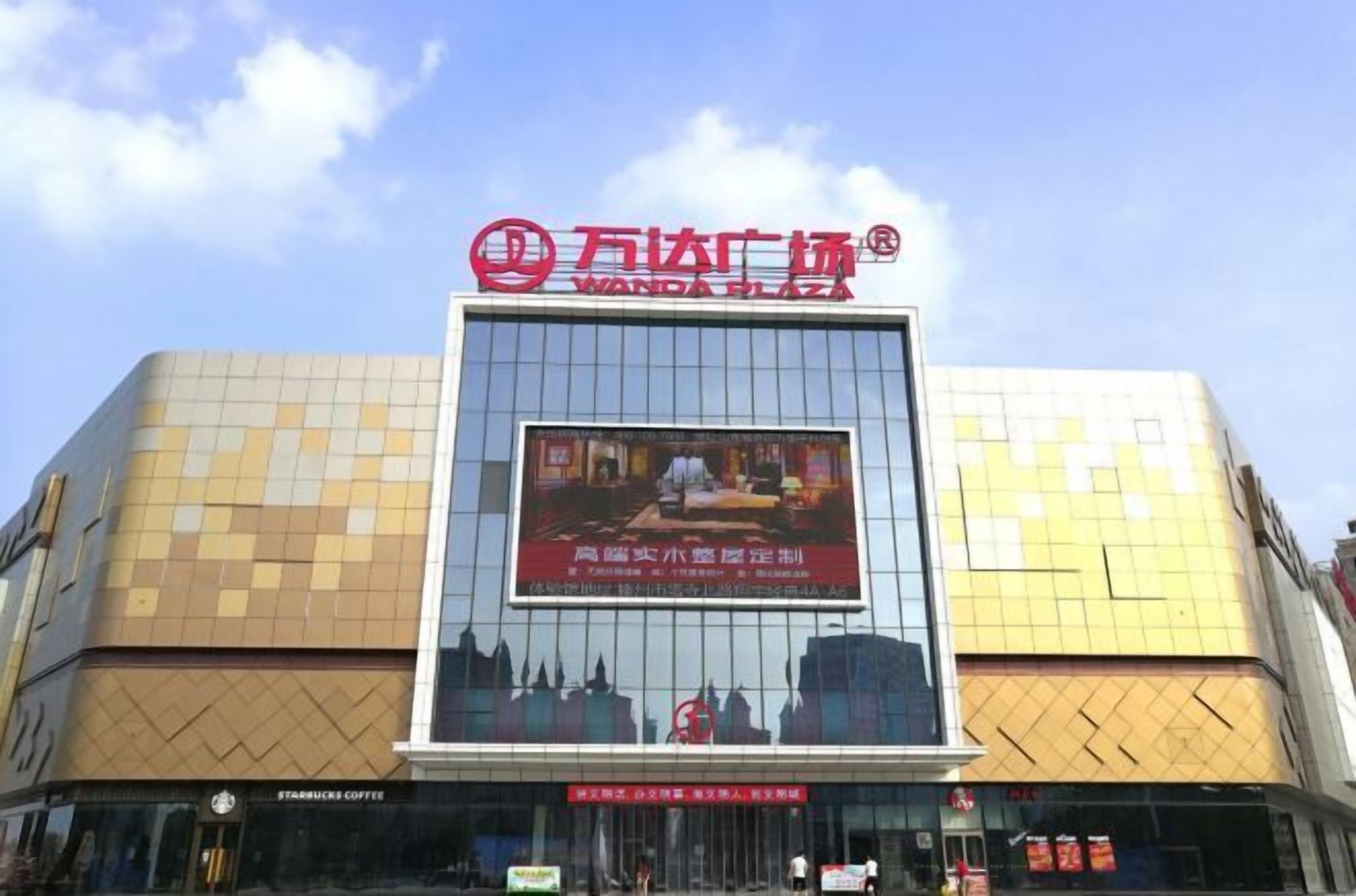 A building with a large sign reading "Wanda Plaza" and a Starbucks Coffee shop at the entrance.