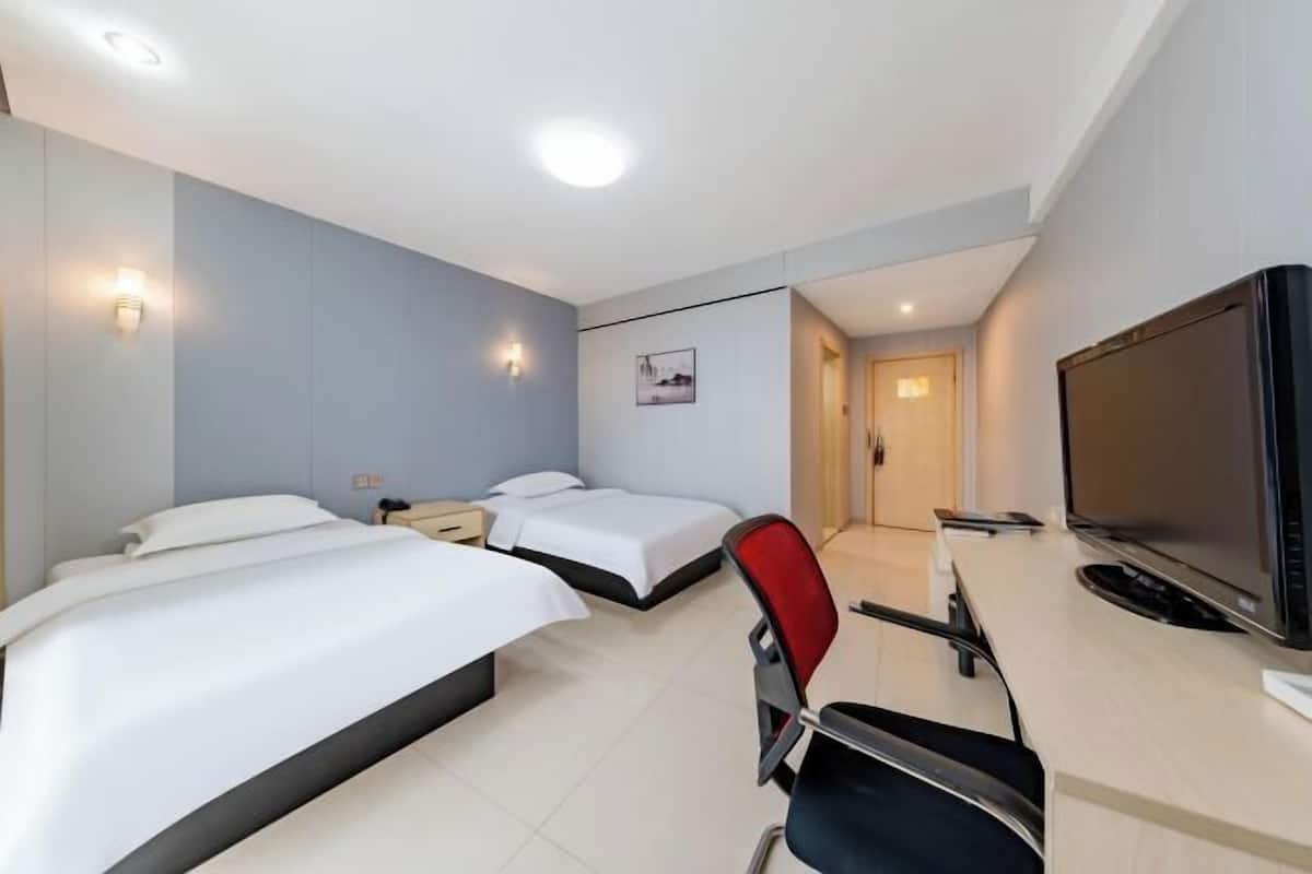A hotel room with two beds, a desk with a chair, a television, and a picture on the wall.