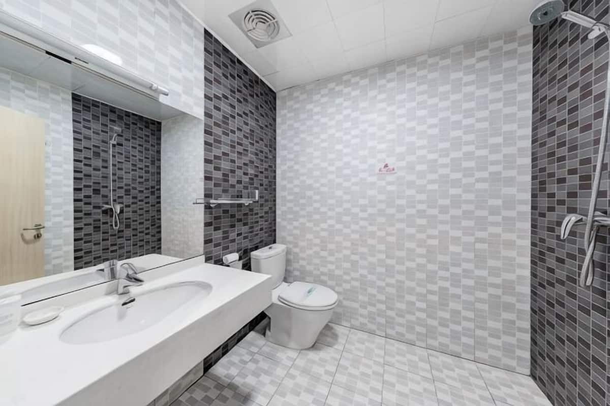 A bathroom with a sink, mirror, toilet, and shower area.