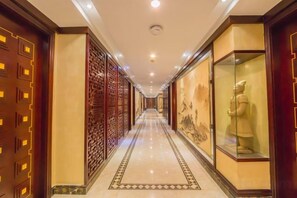 A corridor with patterned walls, a tiled floor, and a statue in a glass case. - Qing He Hotel (Hangzhou)