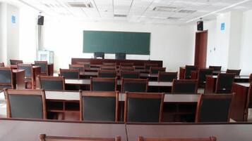 Un aula con filas de escritorios y sillas, una pizarra y un altavoz.
