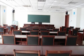 Un aula con filas de escritorios y sillas, una pizarra y un altavoz.