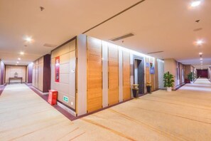 Un pasillo de hotel con piso alfombrado, paneles de madera y una puerta que da a una habitación.