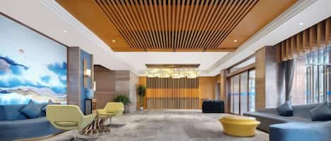 A lobby with a wooden ceiling, a large chandelier, and seating areas with sofas and chairs.