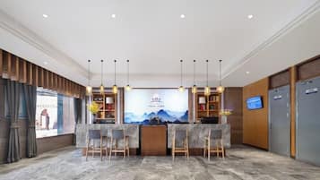 A reception area with a counter, bar stools, a television, and a wall-mounted screen.