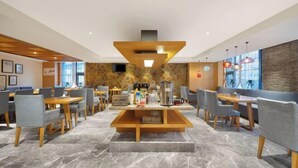 Un comedor moderno con una estación de café central, detalles en pared de piedra y amplios ventanales que permiten la entrada de luz natural.