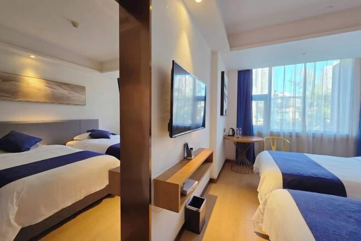 Habitación de hotel con dos camas, televisión, una mesita y ventana con cortinas.