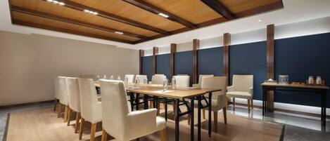 A conference room with a long table, chairs, and a high ceiling with wooden beams.