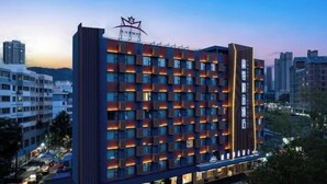 Un hotel moderno con una fachada luminosa, una disposición en cuadrícula de habitaciones y un logotipo de estrella destacado en la parte superior.