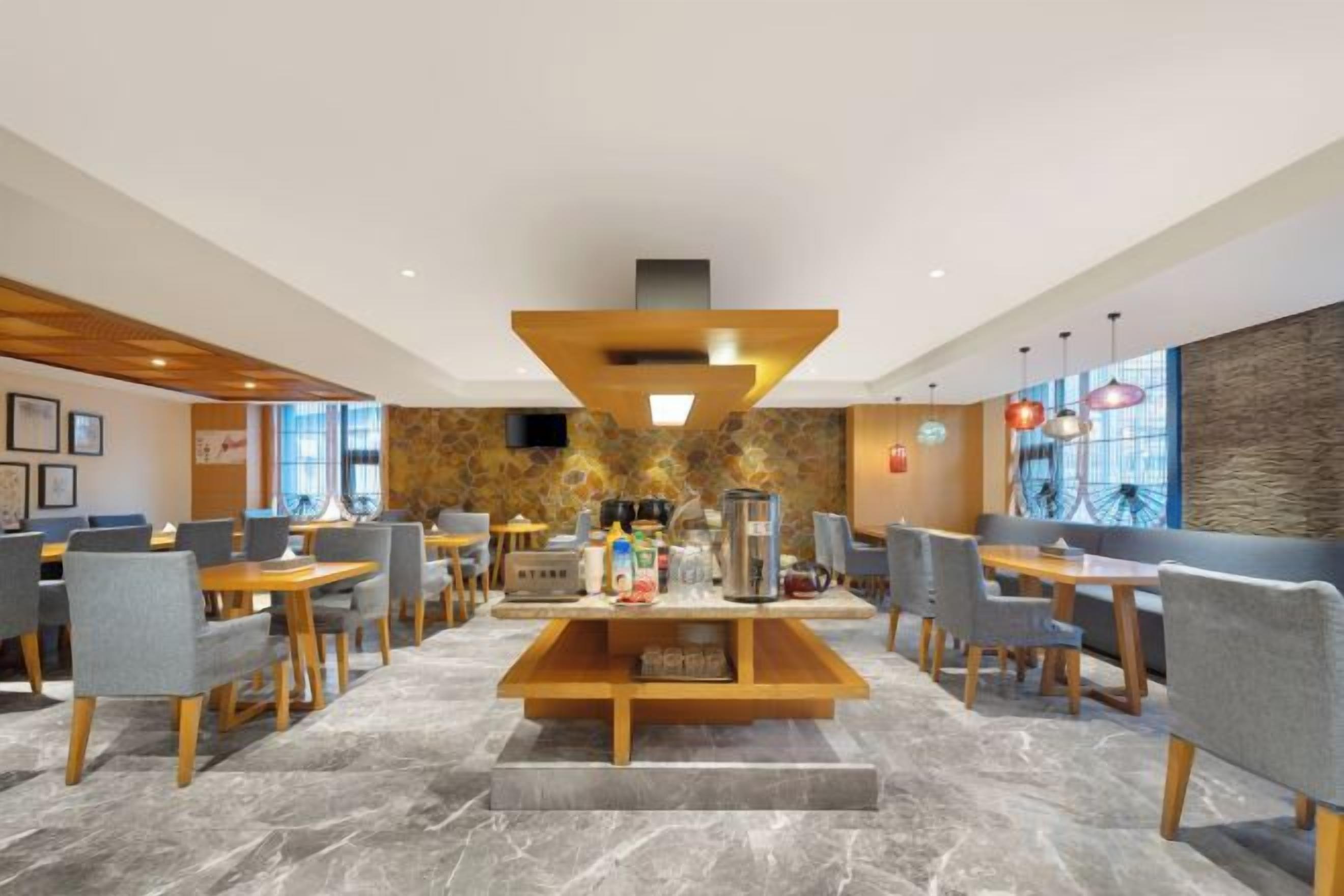 A modern hotel lobby with a central seating area, multiple tables, and chairs.