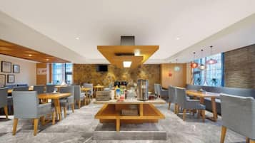 A modern hotel lobby with a central seating area, multiple tables, and chairs.