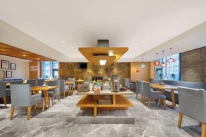 Un moderno vestíbulo de hotel con un área de estar central, varias mesas y sillas.