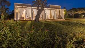 A modern villa with a covered outdoor seating area, a well-maintained lawn, and a large tree in the foreground. - Tenuta Del Leccino - Torre Vado (Torre vado)