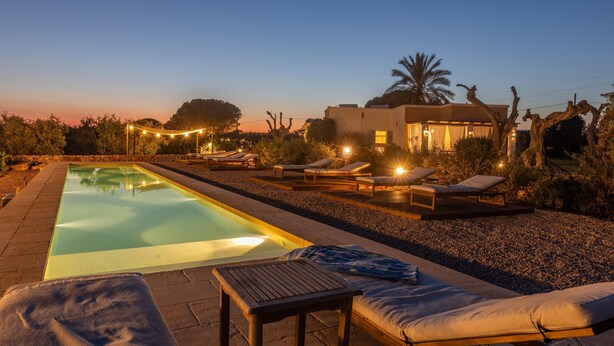 A swimming pool with lounge chairs and a table, surrounded by a pebble garden and a modern house with a visible balcony. - Tenuta Del Leccino - Torre Vado (Torre vado)