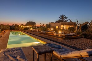 A swimming pool with lounge chairs and a table, surrounded by a pebble garden and a modern house with a visible balcony. - Tenuta Del Leccino - Torre Vado (Torre vado)