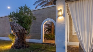 A building entrance with a stone facade, an arched doorway, and a tree in the foreground. - Tenuta Del Leccino - Torre Vado (Torre vado)