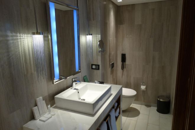 Un bagno moderno con uno specchio grande, un lavandino bianco e un water.