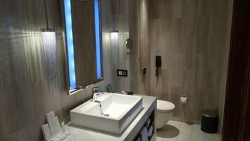 Un bagno moderno con uno specchio grande, un lavandino bianco e un water.