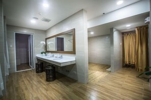 A modern bathroom with a large mirror, white sink, and wooden flooring. - Winford Resort and Casino Manila (City of Manila)
