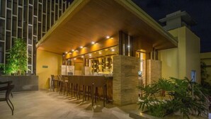 An outdoor bar area with a wooden roof, stone pillars, and a seating arrangement. - Winford Resort and Casino Manila (City of Manila)