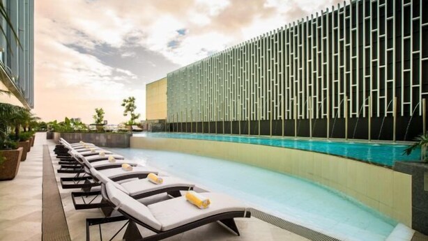 A poolside area with lounge chairs and a modern building with a patterned facade. - Winford Resort and Casino Manila (City of Manila)