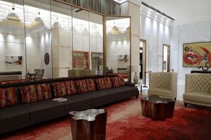 A modern living room with a sofa, armchairs, and a large mirror.