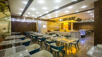 A restaurant with multiple tables and chairs, a bar area, and a counter.