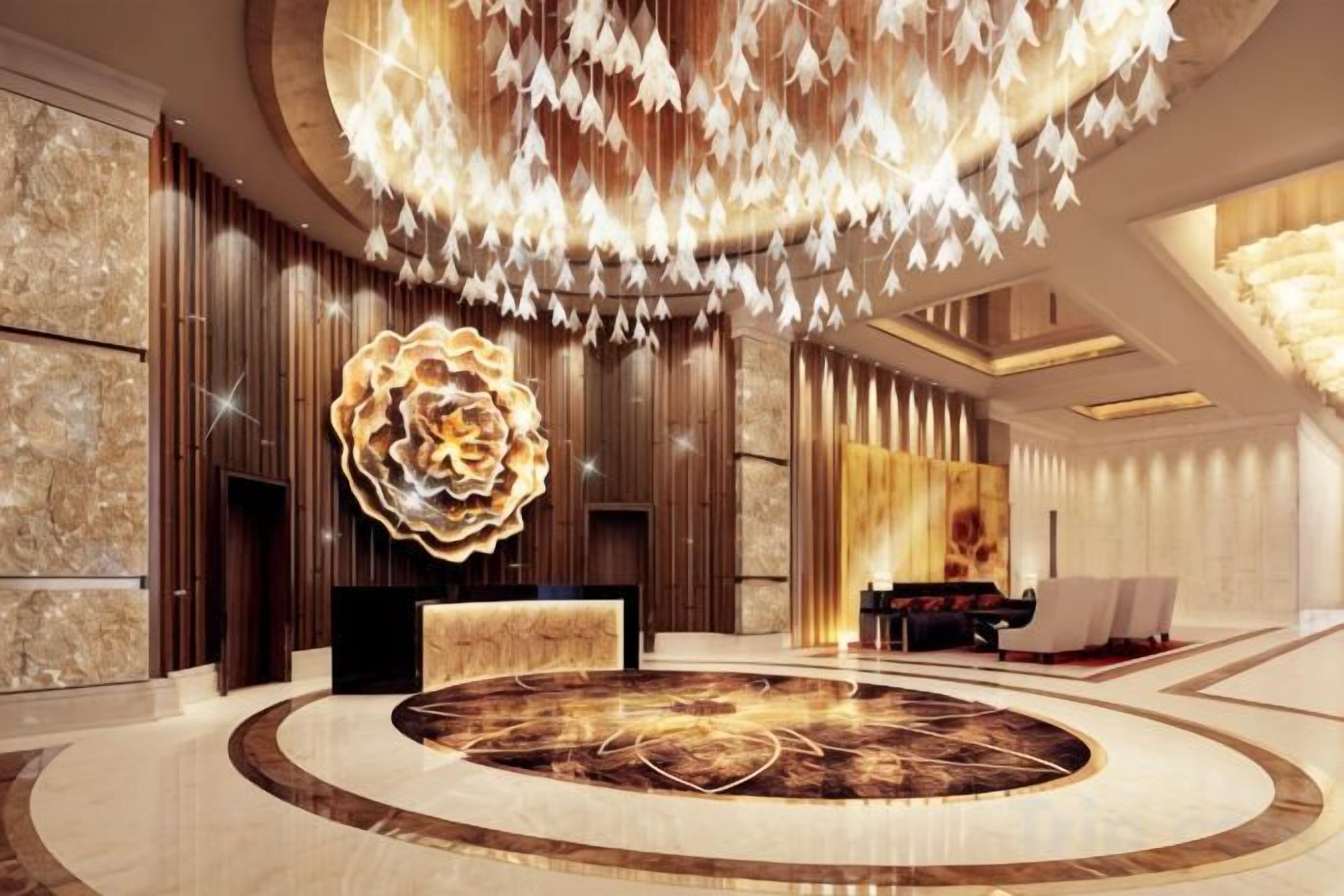 A luxurious lobby with a central circular seating area, a large chandelier, and a modern reception desk.