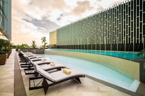 A poolside area with lounge chairs and a modern building with a patterned facade. - Winford Resort and Casino Manila (City of Manila)