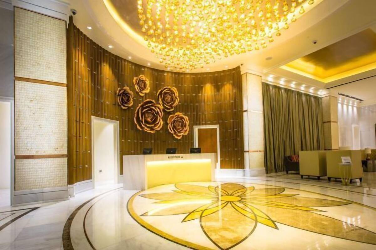 Zona de recepción de hotel con un diseño de piso circular, un mostrador de recepción y una pared con estampado floral.