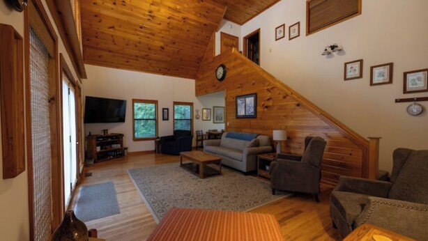 Ein geräumiges Wohnzimmer mit Holzboden, einer Treppe und einem Fernseher.
