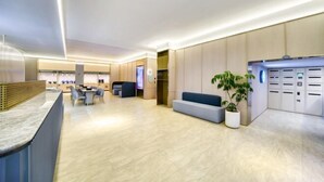 A modern hotel lobby with a reception desk, seating area, and lockers. - HanTing Hotel (Hangzhou Wenyi Road) (Hangzhou)
