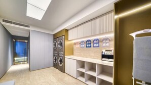 A modern laundry room with a skylight, built-in washer and dryer, and a bench with storage shelves. - HanTing Hotel (Hangzhou Wenyi Road) (Hangzhou)