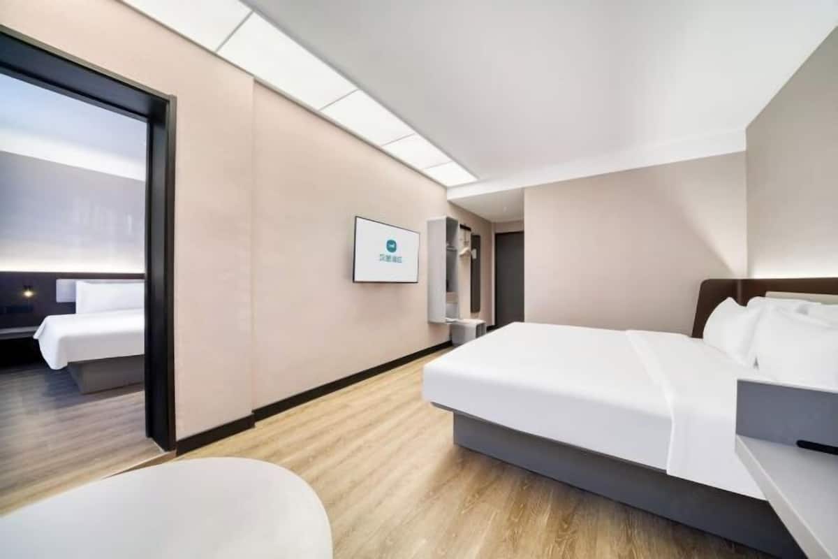 A modern hotel room with a bed, a desk, a chair, and a large window.