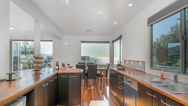 A modern kitchen with wooden countertops, stainless steel appliances, and large windows offering a city view.