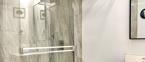 A modern bathroom with a glass-enclosed shower, a white toilet, and a vanity with a mirror.