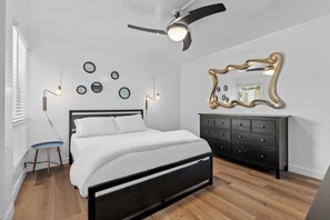 A bedroom with a bed, a dresser, a ceiling fan, and wall decorations. - Primo Scottsdale Location w Heated Pool  (Scottsdale)
