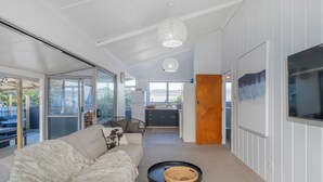 Un salón moderno con un sofá, una mesa de centro y vistas a la cocina y al área exterior.