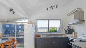 Una cocina moderna con armarios oscuros, un refrigerador blanco y un amplio ventanal.