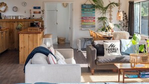 A cozy living room with a sofa, coffee table, and a sign reading "BEACH HOUSE RULES".