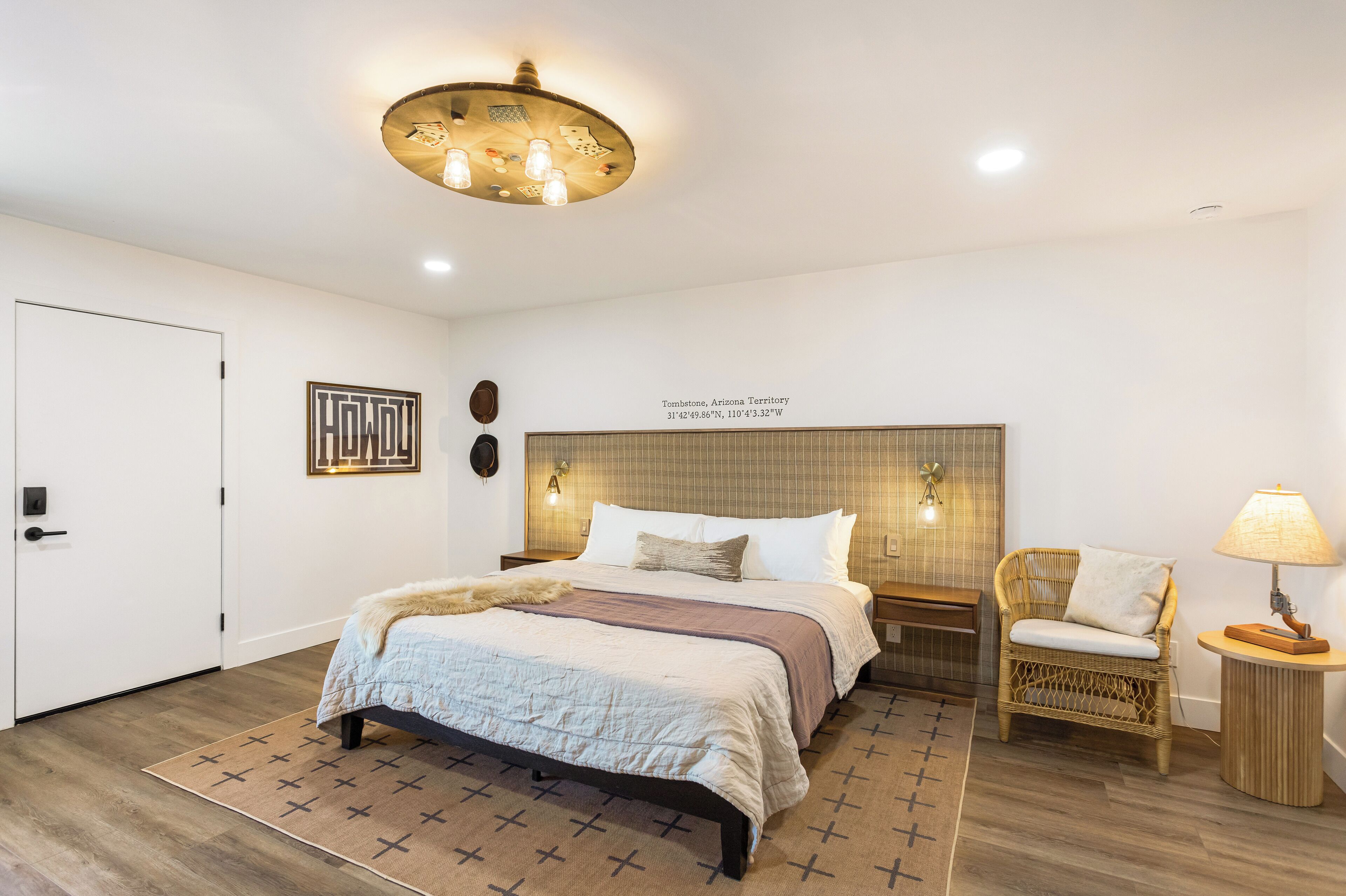 A bedroom with a bed, a chair, a lamp, and a wall-mounted light fixture.