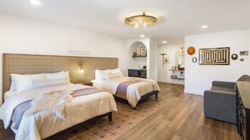 Une chambre d’hôtel avec deux lits, un canapé, un plancher en bois et un luminaire au plafond.
