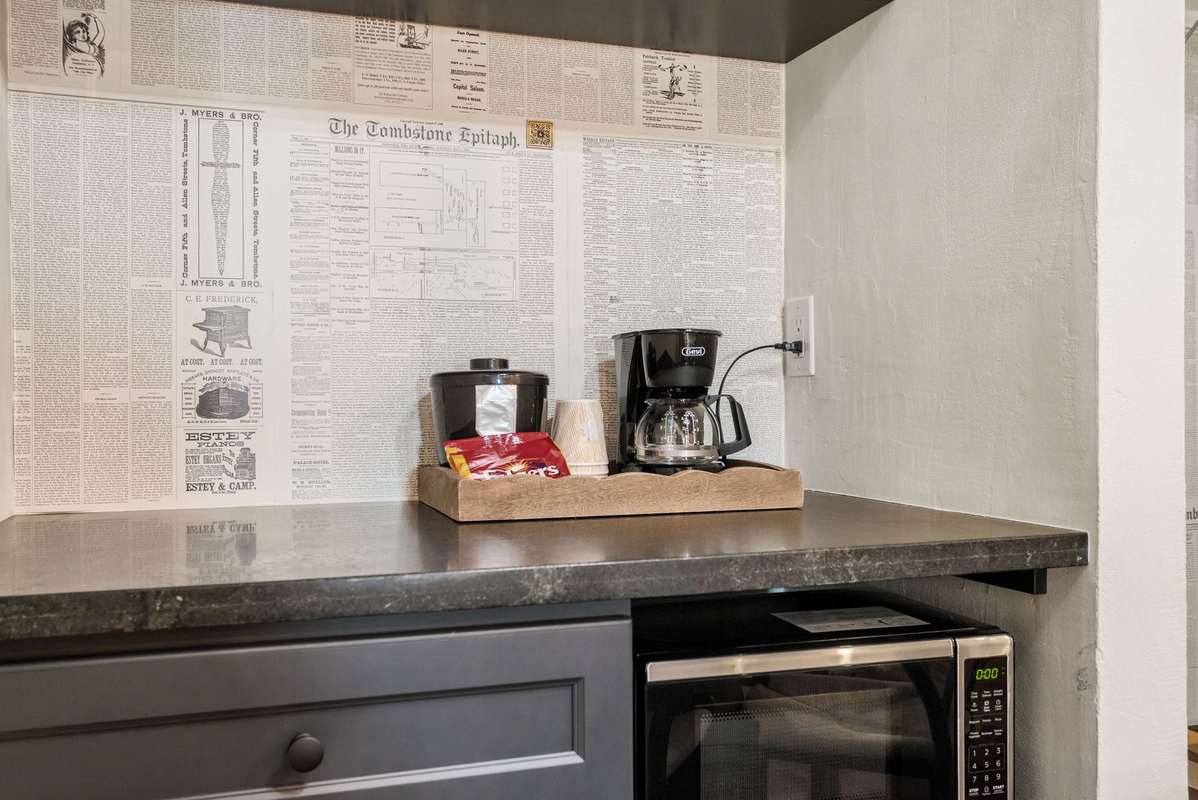 A kitchen counter with a newspaper, a coffee maker, and a microwave.