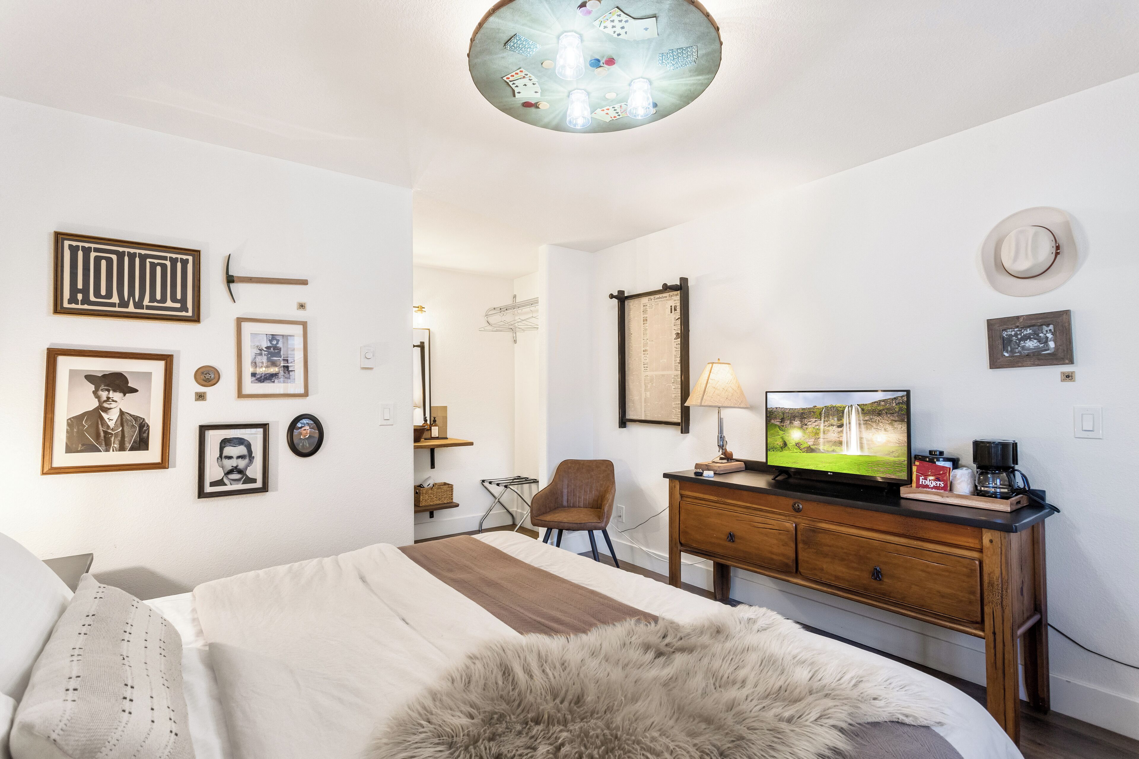 Une chambre à coucher comprenant un lit, une commode en bois, un téléviseur et divers tableaux encadrés accrochés au mur.