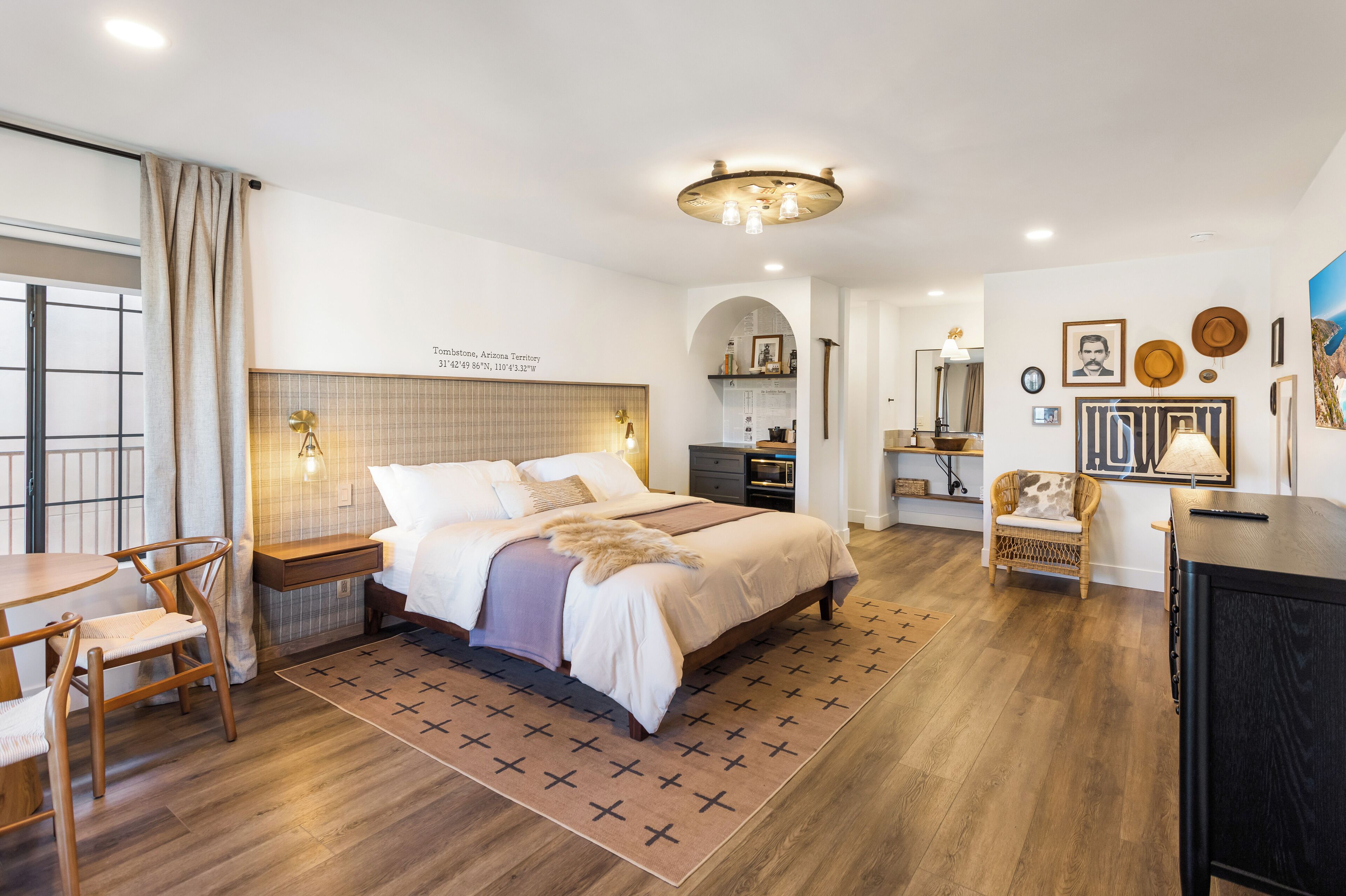 A hotel room with a large bed, a desk, a chair, and a wardrobe.