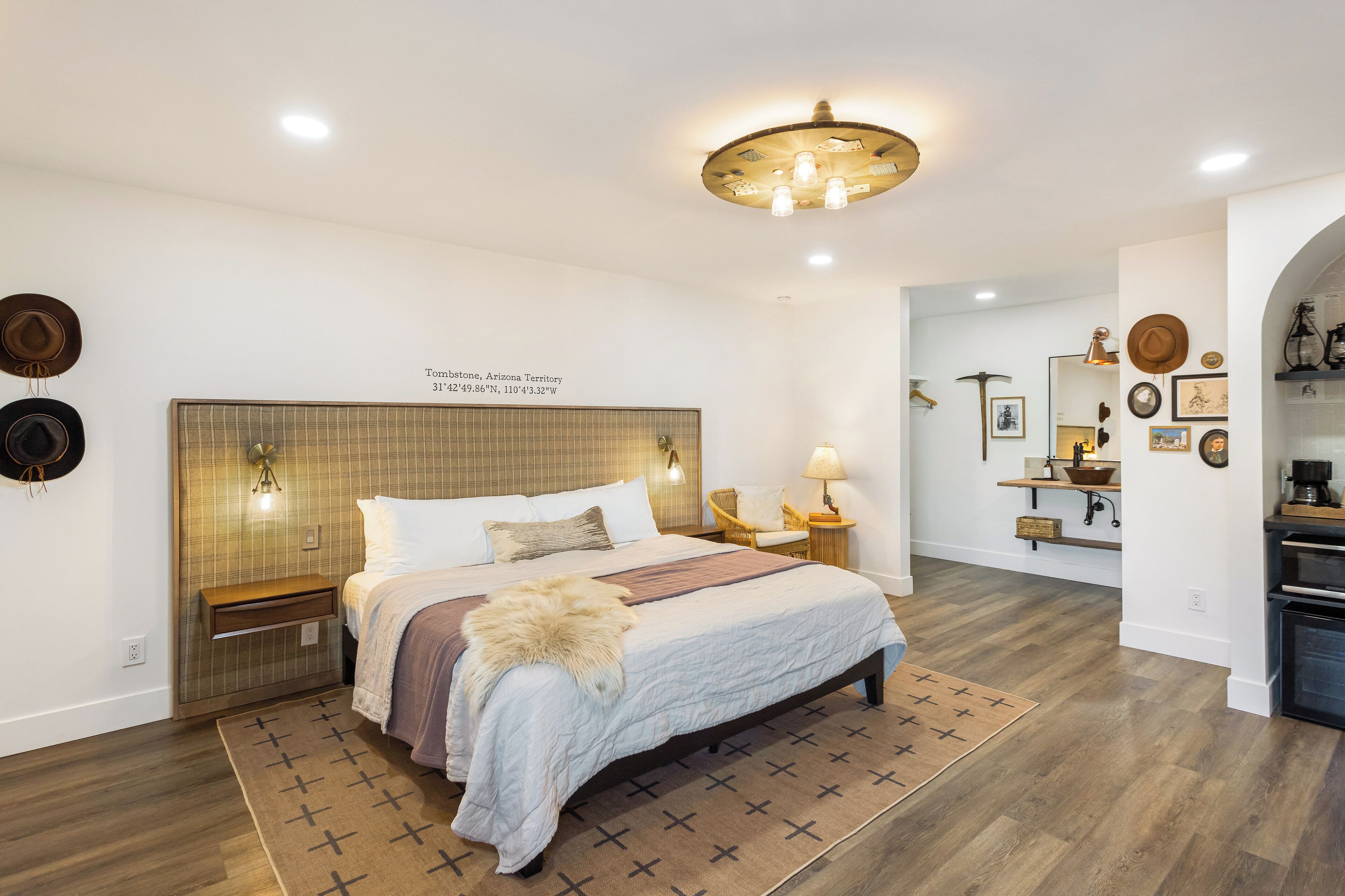 Un dormitorio con una cama grande, un cabecero de madera, lámparas de noche, una mesita de noche y una alfombra.