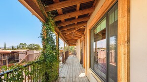 A wooden balcony with a view of the surrounding area, including a building and trees.