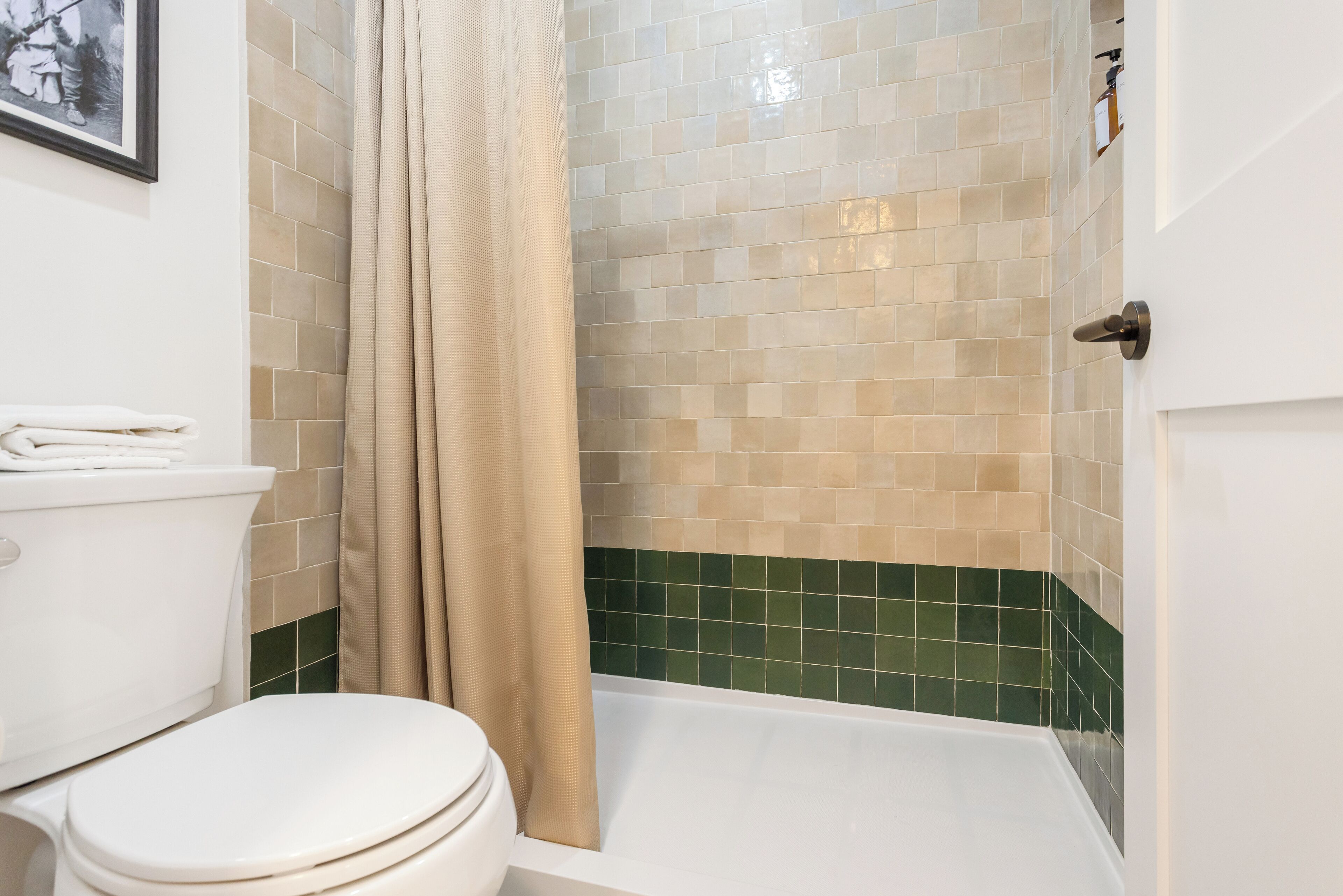 A bathroom with a toilet, shower, and tiled walls.