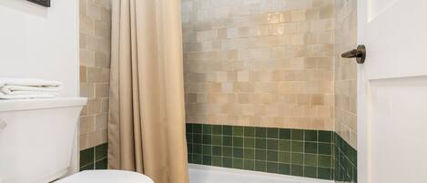 A bathroom with a toilet, shower, and tiled walls.
