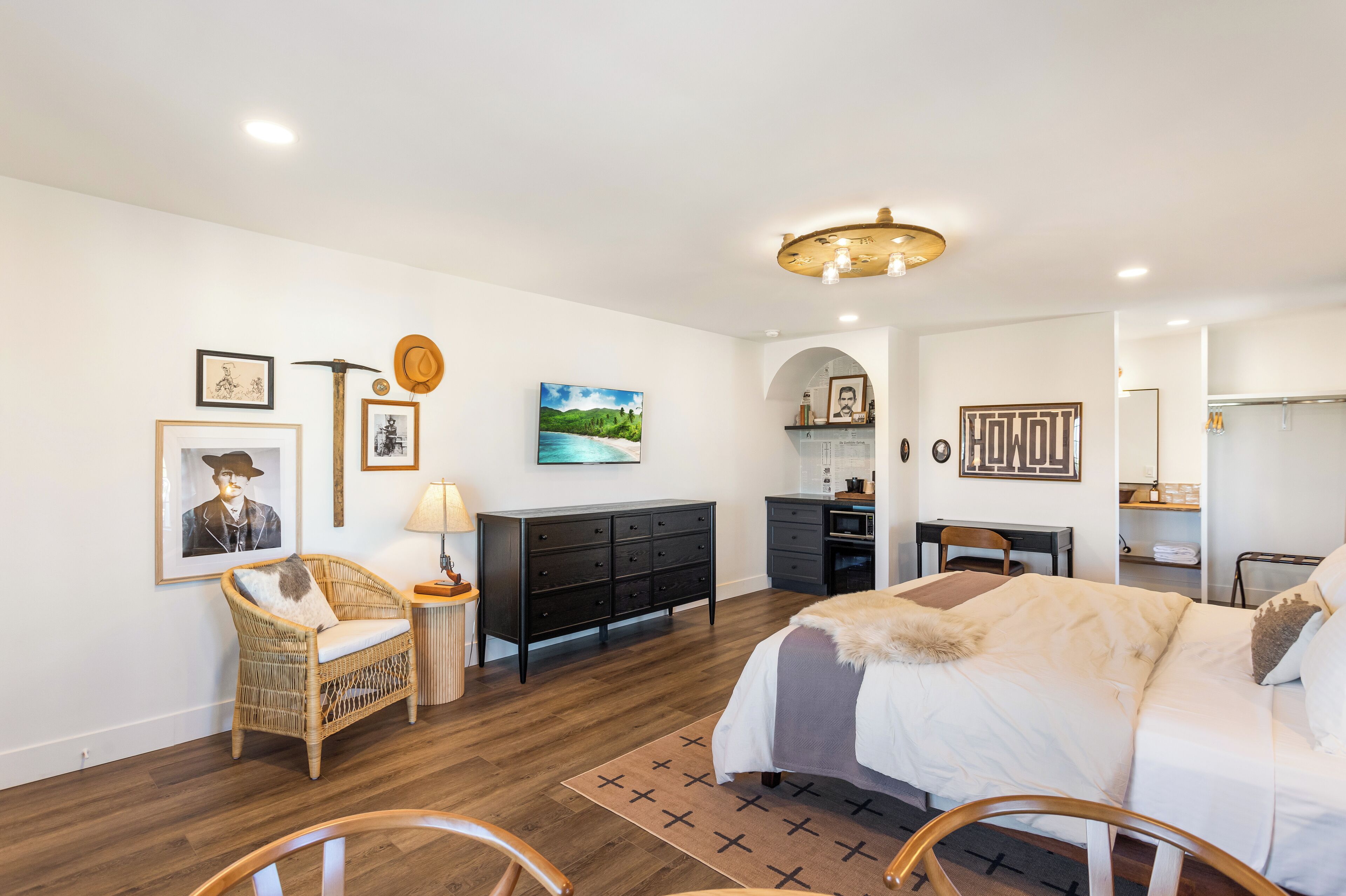 Une chambre à coucher avec un lit, une commode, une chaise, un bureau et un téléviseur.